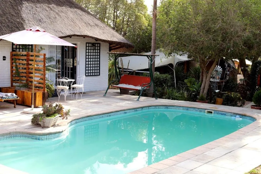 The swimming pool in front of a thatched guest suite at House of Perez